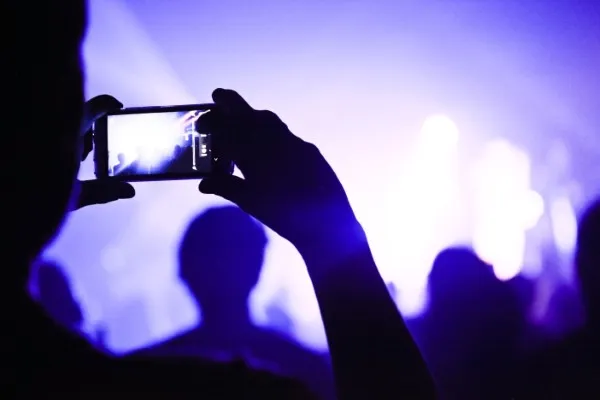Expert social media specialist using a phone to record an event, ready to share engaging content with followers.